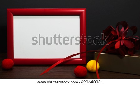 Blank photo red frame on the table with gold gift box with red ribbons.