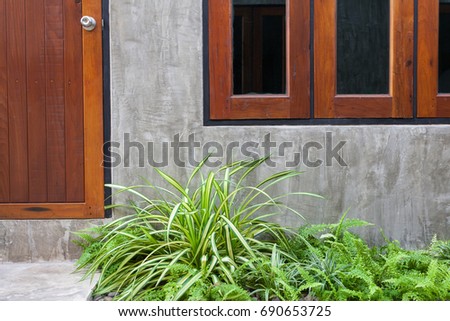 Architecture outdoor exterior modern design. Wooden door and window on cement concrete wall background. Green bush garden.