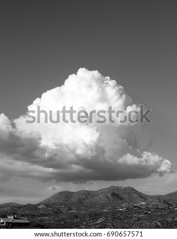 Black and white photo of huge puffy white monsoon clouds framing the Catalina mountains on a sunny day in the  tucson arizona desert vertical
