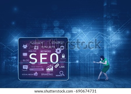 Photo of young businesswoman pulling a billboard with SEO design