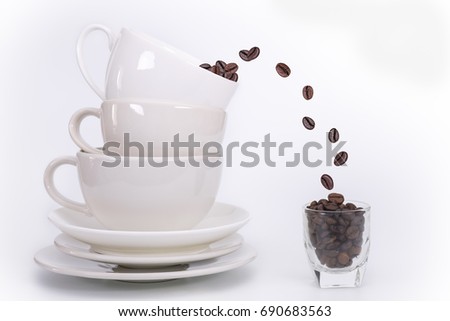 White Ceramic Coffee Mug Stacked And coffee beans fall into the glass isolated on white background.