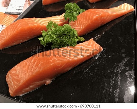 The raw salmon are sold on the black plate in the market. Raw Salmon are displayed with sushi to show how fresh to customers.