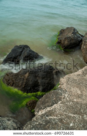 Sea shore with big stones and green moss on slow shutter speed