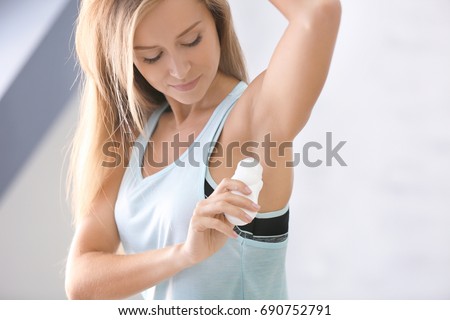 Beautiful young woman with deodorant at home Royalty-Free Stock Photo #690752791