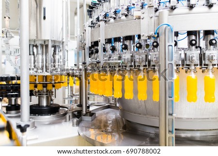 Bottling factory - Orange juice bottling line for processing and bottling juice into bottles. Selective focus.  Royalty-Free Stock Photo #690788002