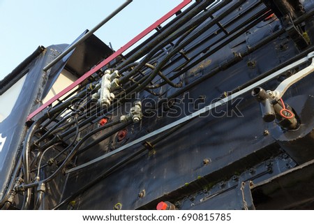 photographed close up an old steam locomotive in black. The photo was taken up in red. Blue sky in the background
