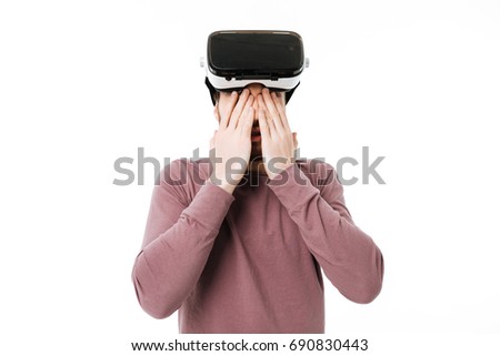 Portrait of young boy closing his eyes with hands wearing visual reality glasses on white background. Man playing with virtual reality glasses isolated 