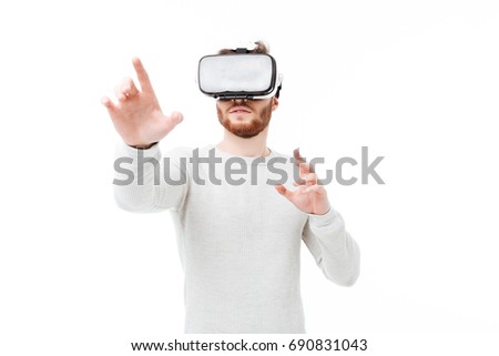 Portrait of young man in studio using virtual reality glasses on white background. Cool boy playing with visual reality glasses isolated