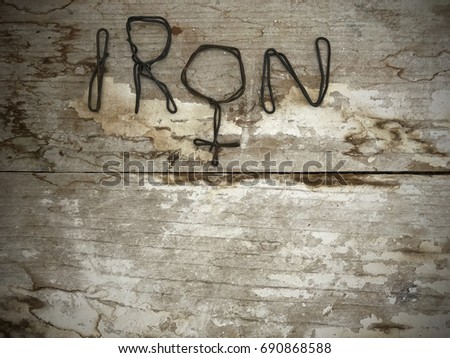 Iron man text made from steel wire. One letter is placed with male symbol. Bent metal text placed on wooden rustic and old surface. Empty space on down side for own texture or information