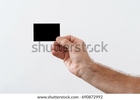 man's hand holds a black paper for inscription
