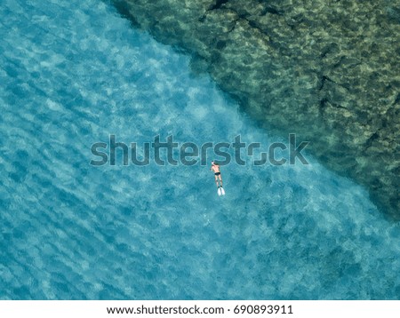 Aerial view of rocks on the sea. Overview of seabed seen from above, transparent water. Swimmers, bathers floating on the water