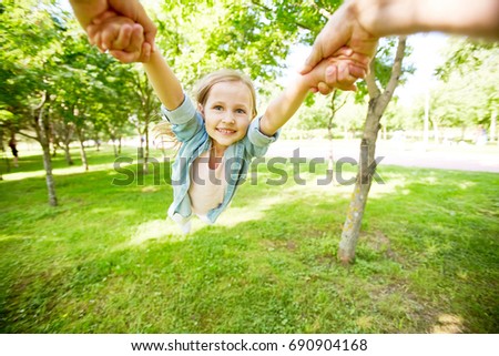 Hands of parent holding little girl and whirling her in park Royalty-Free Stock Photo #690904168