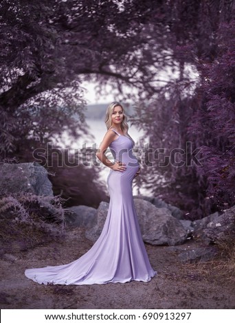 Attractive pretty woman in creative purple dress silhouette mermaid long lace train. Fantasy picture pregnancy blonde cute girl. Smiling happy face. Enjoying nature Park river rocks. Long curly hair