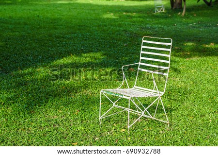 white iron chair under shadow tree on green glass field
