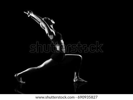  low key black and white studio picture of a yoga warrior pose isolated on black