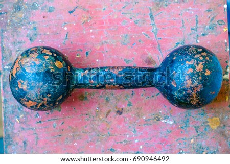 Old dumbbell. One dumbbell with an old cracked paint. Red grange background