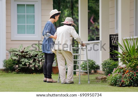 Elderly woman exercise walking in backyard with daughter Royalty-Free Stock Photo #690950734