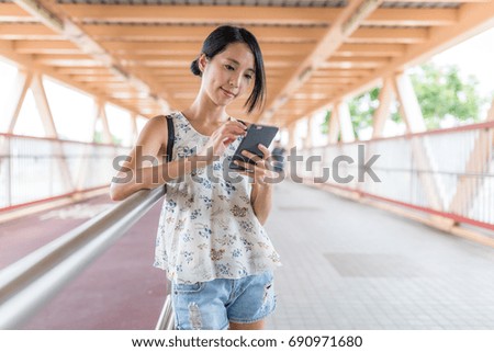 Woman looking at mobile phone in the foot bridge