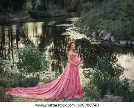 Cute woman in a beautiful dress with a long train. Fantastic picture of pregnancy. Creative colors.