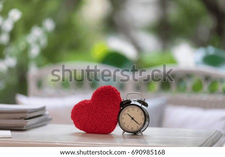 blue retro heart shape clock with red heart knitting shape on wooden mock up over blurred green garden on day noon light,Image for happy valentine day decoration concept. over blurred green garden.
