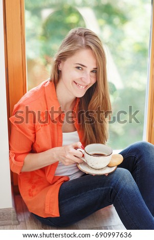 Portrait og young woman with cup of coffee and cookies