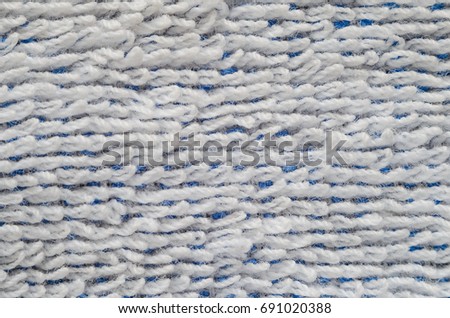 Macro shot of a white towel. Texture is similar to the texture of a fleecy knotted-pile carpet. Geometric pattern of villi on fabric material. White villi on a blue base