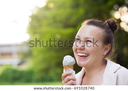 Pretty young brunette woman with ice cream i n the park, smilling, laughing