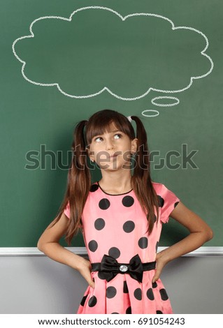 child near school blackboard with blank speech bubble 
