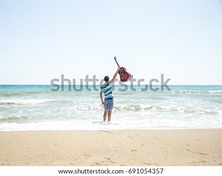 young man with acoustic guitar on the beach, joyful emotions, the concept of leisure and music
