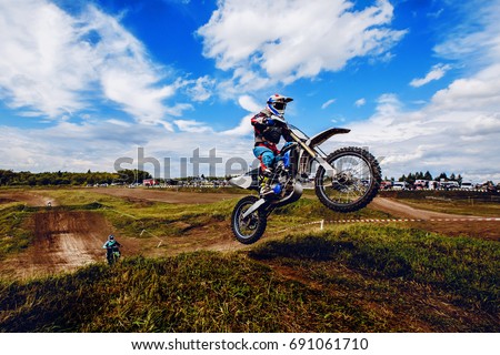 racer on mountain bike participates in motocross race, takes off and jumps on springboard, against the background of the participants. Close-up. concept of extreme rest, sports racing.