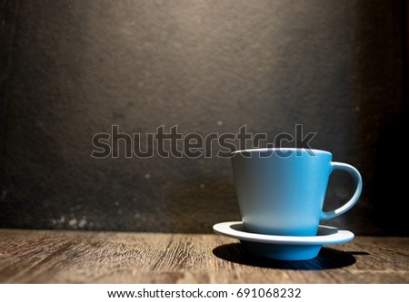 Cup of coffee on old wooden desk. Simple workspace or coffee break in holiday (selective focus).