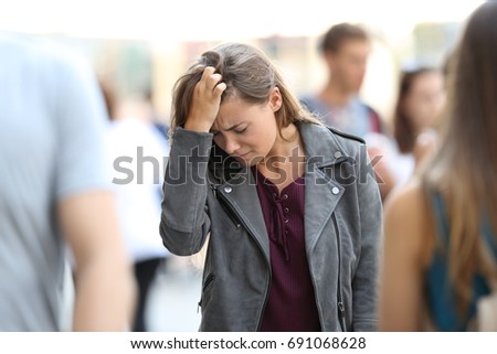 Depressed teen feeling lonely walking on the street surrounded by people Royalty-Free Stock Photo #691068628