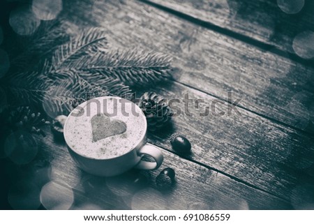 Cup of coffee with heart shape and pine cone with acorn on wooden background