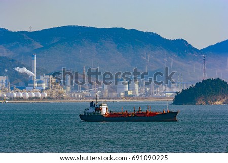 Liquefied Petroleum Gas (LPG) tanker anchored near the shore with the facilities of the oil refinery and mountain range in the background. Port of Gwangyang, Jeonnam, Korea.