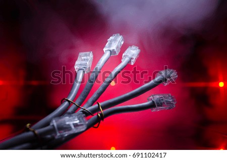 Network switch and ethernet cables, symbol of global communications. Colored network cables on dark background with lights and smoke. Selective focus. Network internet concept background