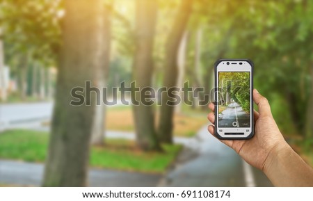 Tourist taking a picture of road lake using a smartphone, point of view shot