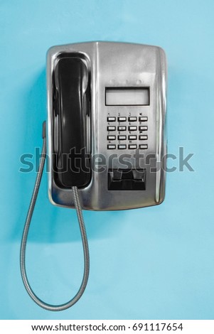 Metal Public Telephone on blue wall. Old payphone concept Royalty-Free Stock Photo #691117654
