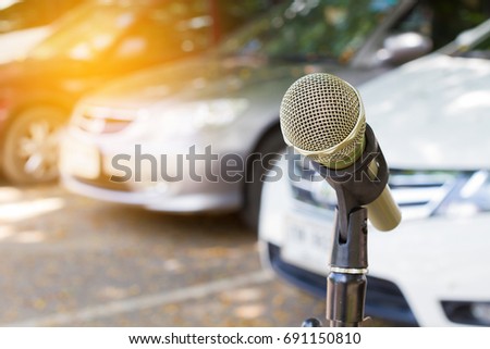 microphone on a stand with blurred vehicles in car park background, Copyspace on the left.