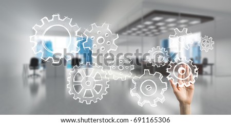 Close of businesswoman hand touching gears on screen with palm and office at background