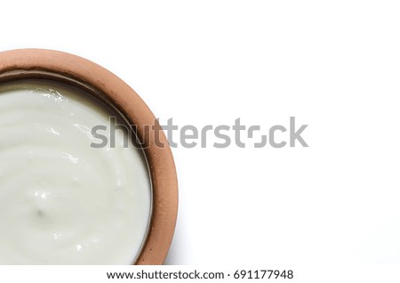 a pottery dish with yogurt on a white background