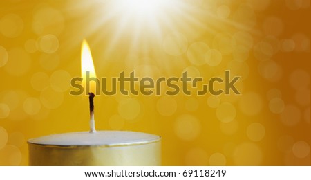 one burning candle with bright white light and orbs
