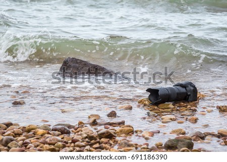 DSLR camera with telephoto lens on a beach it wet from water sea wave when travel
