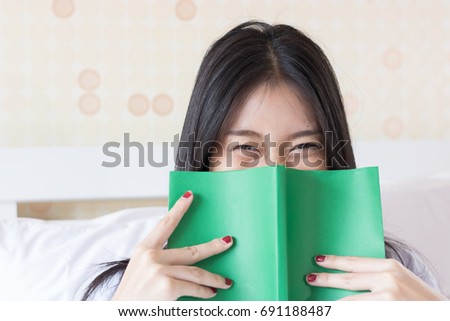 Happy Asian woman reading a book on bed.