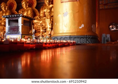 Fire light from red candle.Glass candle on wood table.Ligth reflection on wooden