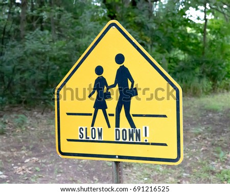 School crossing sign on post with additional slow down lettering Royalty-Free Stock Photo #691216525