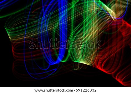 Light painting abstract background. Bright glow light tracks against dark surrounding area.