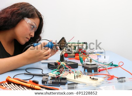 Electronic workshop, young lady soldering components of an Arduino project