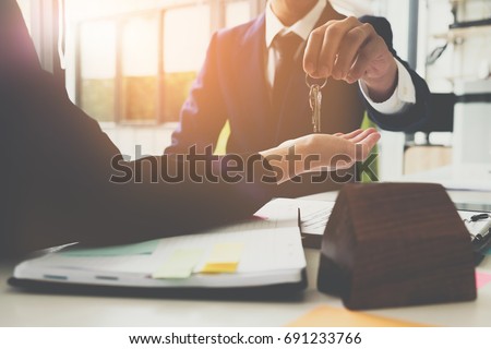 estate agent giving house keys to woman and sign agreement in office Royalty-Free Stock Photo #691233766