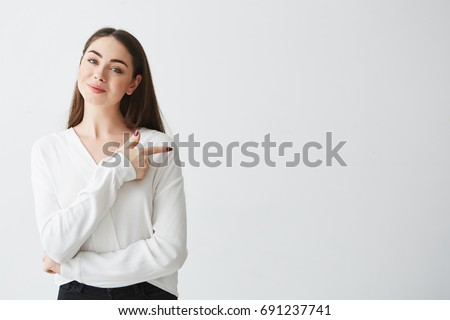 Young beautiful brunette businesswoman smiling looking at camera pointing finger in side over white background. Royalty-Free Stock Photo #691237741