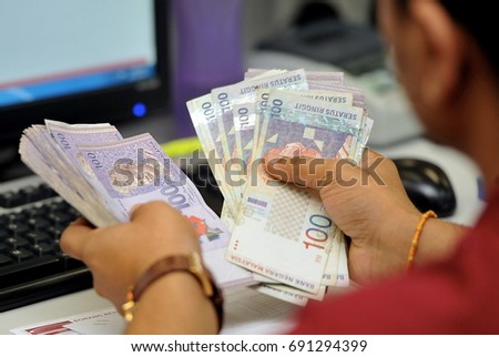 The Malaysian Ringgit (MYR) being counted at a money changer Royalty-Free Stock Photo #691294399